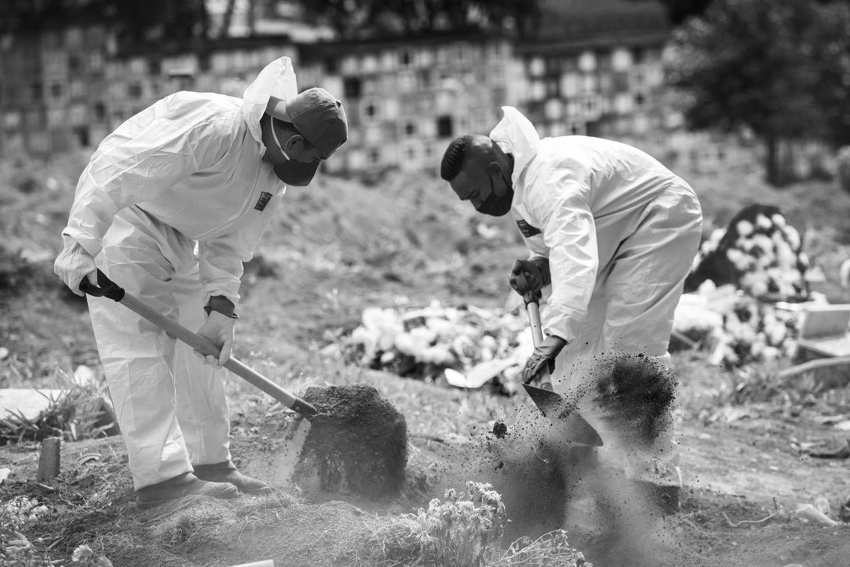 Sepultadores trabalham durante enterro de uma vítima morta pela Covid-19, no cemitério da Vila Formosa, zona leste paulistana, em 13.mai.2020 