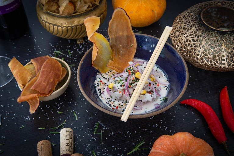 A foto mostra uma cerâmica escura com ceviche de peixe branco e cips de batata doce