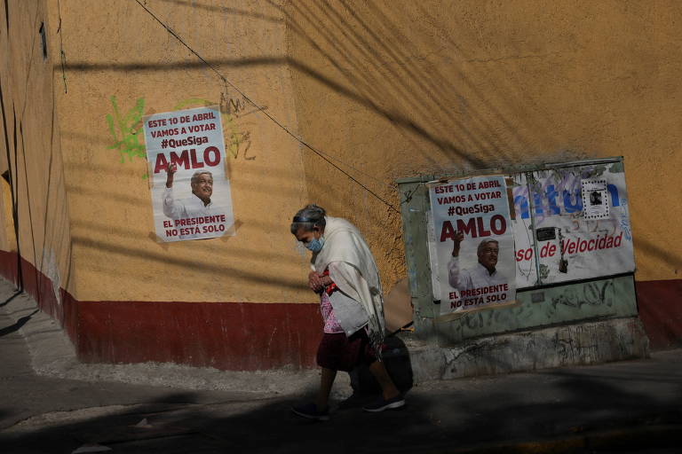 Idosa passa em frente a cartazes convocando para a votação de referendo revogatório sobre o mandato do presidente AMLO, na Cidade do México 

