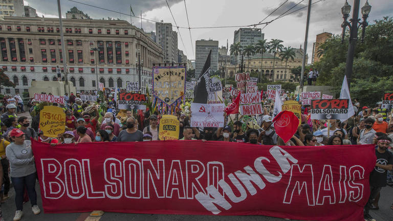 Imagem mostra rua ocupada por manifestantes, que seguram uma faixa vermelha com os dizeres "Bolsonaro nunca mais".