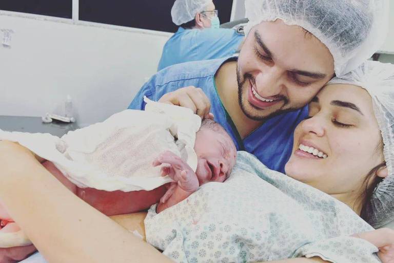 Casal com bebê recém nascido em quarto de hospital