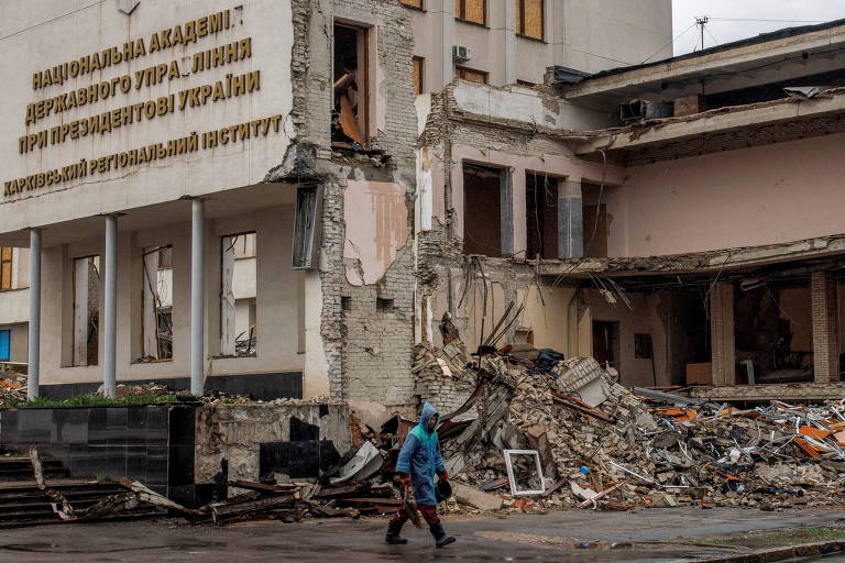 Homem caminha em Kharkiv diante de prédio da Academia Nacional de Administração Pública, parcialmente destruído em ataque