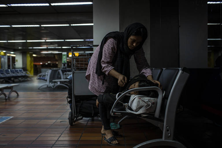 Khalida arruma o cobertor de um dos filhos, que dorme no banco do aeroporto