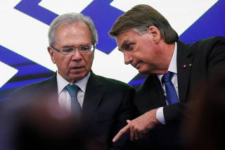 Brazil's President Jair Bolsonaro talks with Brazil's Economy Minister Paulo Guedes during a Brazil's Banco do Brasil credit launching ceremony for truck drivers in Brasilia