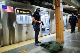 A New York Police Officer of the anti terrorism unit prepares to inspect a jacket left in a train as he patrols the 36th St. subway station, a day after a shooting incident took place in the Brooklyn borough of New York
