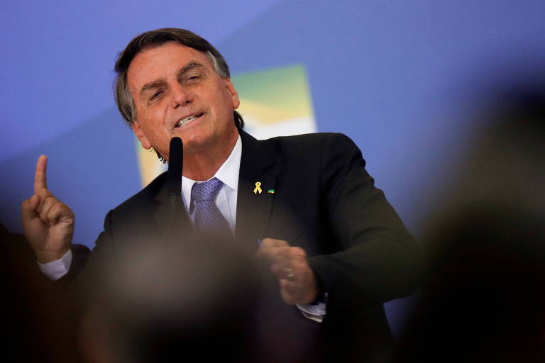 O presidente Jair Bolsonaro gesticula enquanto fala em microfone