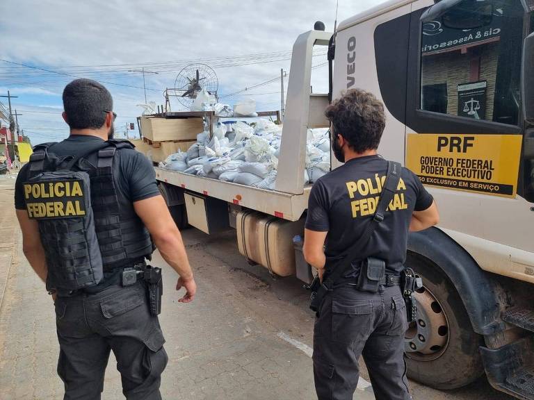 Policiais federais observam a carga de cassiterita ilegal apreendida em Boa Vista (RR)