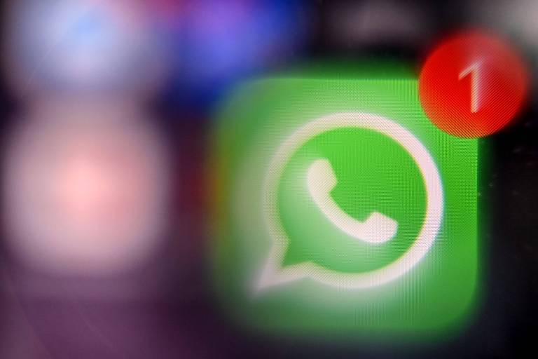 A imagem mostra o ícone do aplicativo WhatsApp em um fundo desfocado. O ícone é de cor verde com um balão de fala branco e um símbolo de telefone dentro. No canto superior direito， há uma notificação em vermelho com o número 1， indicando uma nova mensagem.