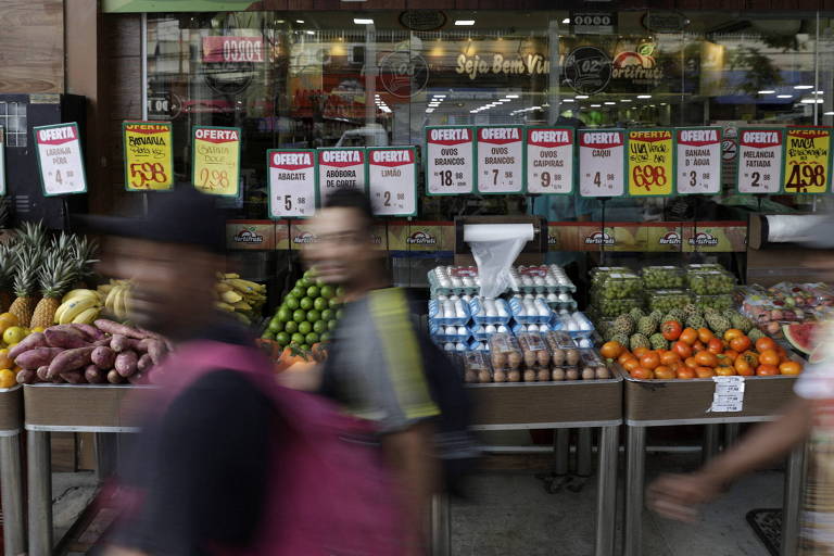 Consumidores passam por bancas com preços de alimentos em mercado do Rio de Janeiro