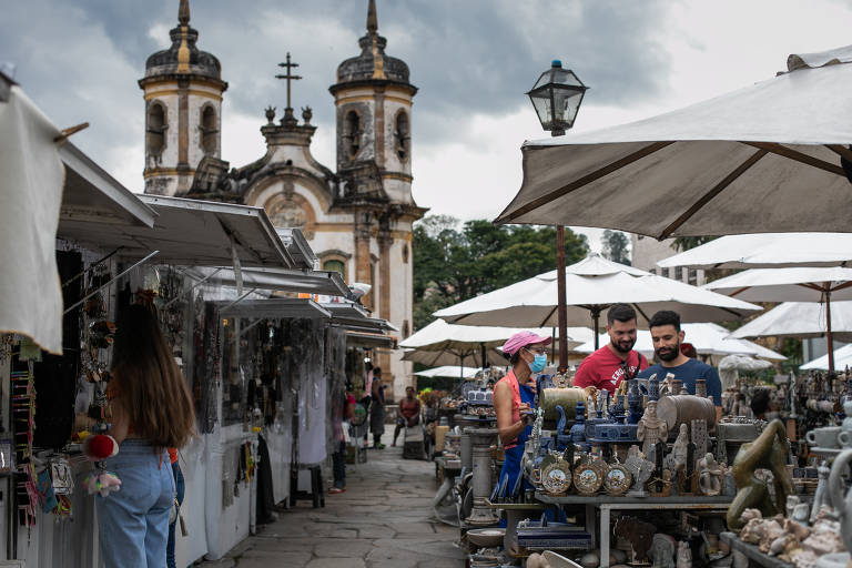 Turistas caminham em uma feira de artigos religiosos e lembranças, em frente a uma igreja