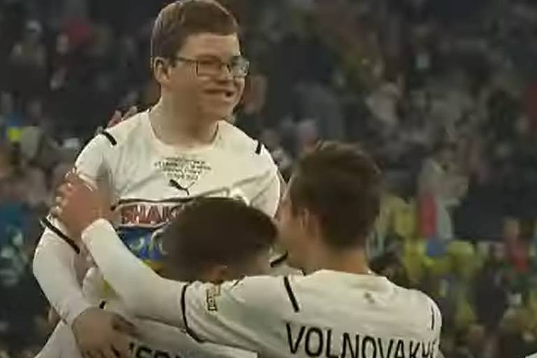 Jogadores do Shakhtar Donetsk festejam com Dmytro Keda, erguendo-o, o gol que o garoto de 12 anos fez em jogo amistoso na Polônia; Dmytro tem os cabelos curtos e usa óculos 