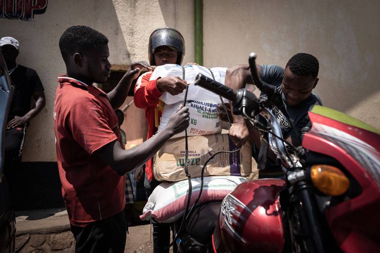 Homens carregam saco de trigo em motocicleta em Kigali, capital de Ruanda; guerra na Ucrânia elevou preço do produto 