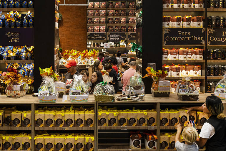 Imagem geral da loja de fábrica da Cacau Show, mostra movimentação de consumidores comprando vários tipos de ovos de páscoa distribuídos nas prateleiras por todo o espaço
