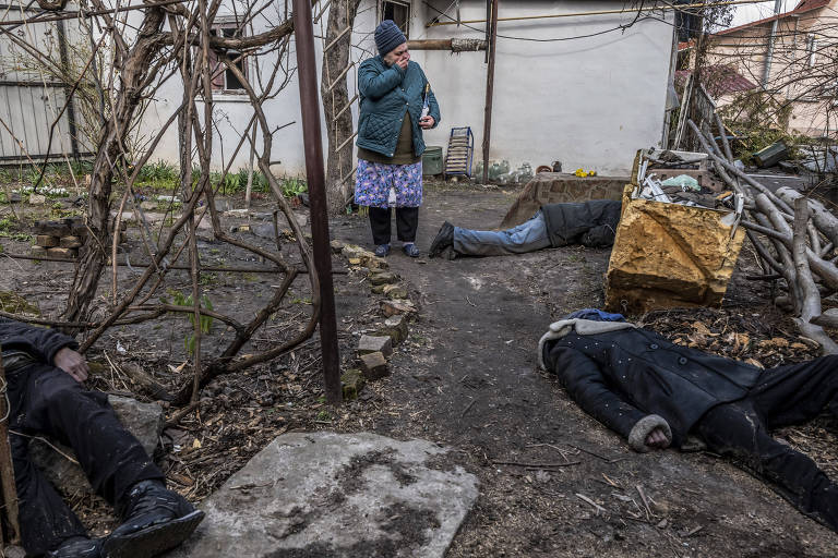 Tetiana Petrovna em jardim onde Roman Havriliuk, o irmão dele, Serhi Dukhli, e uma vítima não identificada foram encontrados em Butcha, na Ucrânia