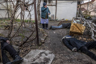 Tetiana Petrovna reacts in the garden where Roman Havryliuk, his brother Serhiy Dukhli and an unidentified victim were found in Bucha, Ukraine, 4, 2022. (Daniel Berehulak/The New York Times)