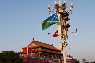 FILE PHOTO: National flags of Solomon Islands and China flutter at the Tiananmen Square in Beijing