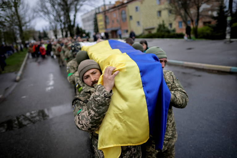 Em fila, soldados com uniformes camuflados carregam caixão coberto com a bandeira da Ucrânia