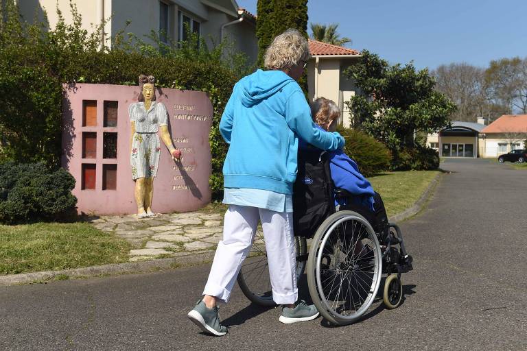 Enfermeira empurra mulher idosa em cadeira de rodas