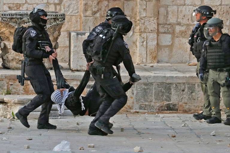 Policiais israelenses levam palestino ferido durante confronto no complexo da mesquita de Al-Aqsa, em Jerusalém
