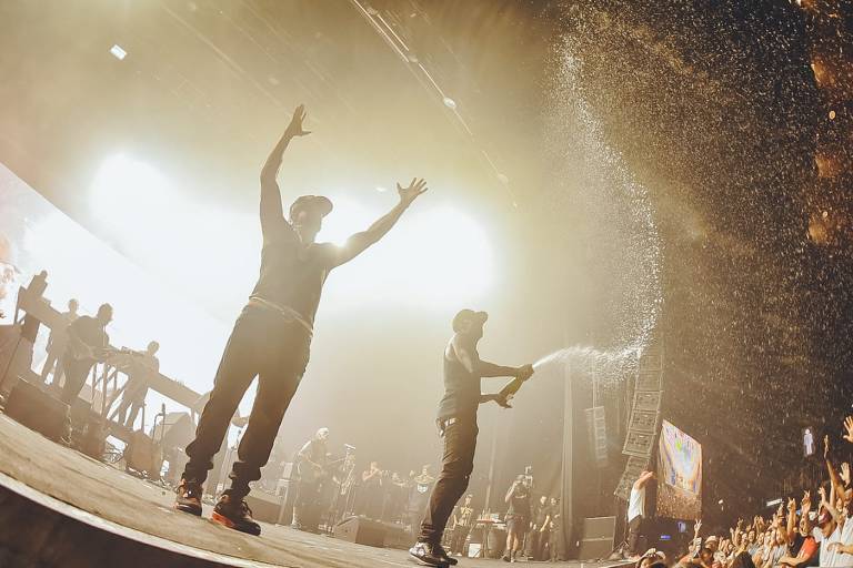 Mano Brown (esq.) e Ice Blue com garrafa de espumante na mão em show do Racionais MC's no Espaço das Américas (zona oeste de São Paulo)