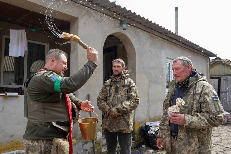 Capelão militar borrifa água benta sobre soldados ucranianos que celebram a Páscoa Ortodoxa na região de Kharkiv 