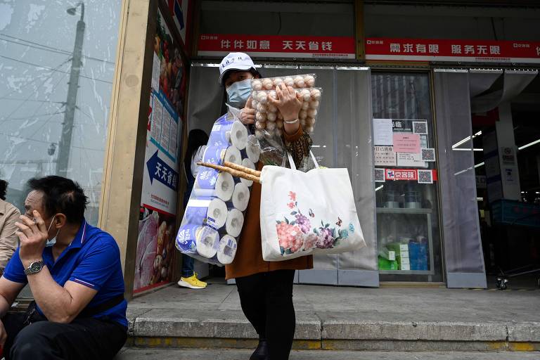 Mulher sai de mercado carregando caixas de ovos e pacotes de papel higiênico