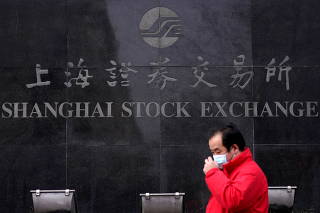 FILE PHOTO: FILE PHOTO: A man wearing a mask walks by the Shanghai Stock Exchange building at the Pudong financial district in Shanghai