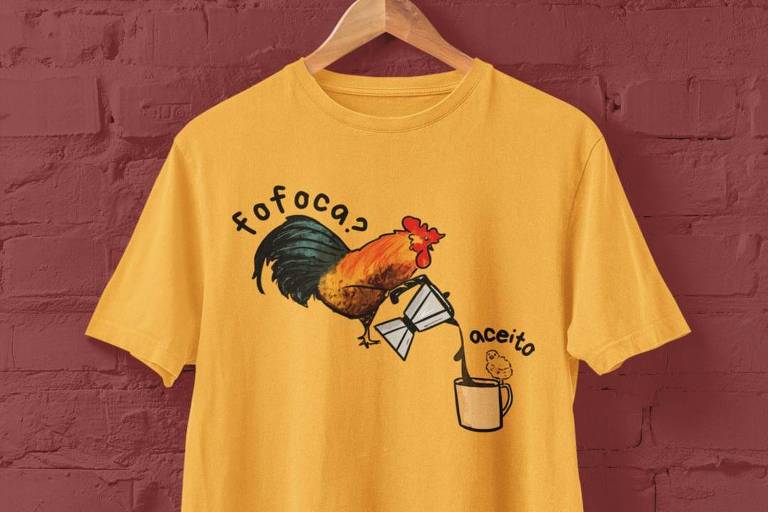 Camiseta amarela com ilustração centralizada de um galo segurando um bule e servindo café a um pintinho, que está apoiado em uma xícara; em volta do desenho, estão os dizeres: 'Fofoca? Aceito'