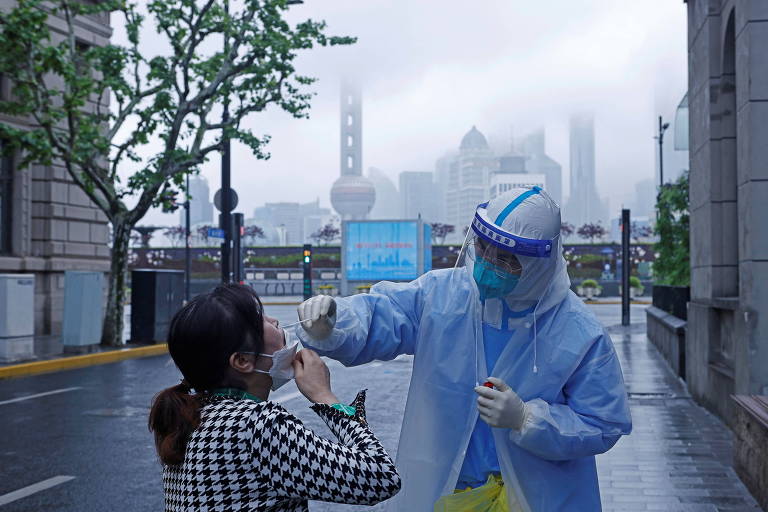 Profissional de saúde coleta amostra de swab de um residente de Xangai, em meio ao surto de Covid-19 na cidade