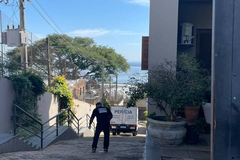 homem com roupa preta escrito polícia civil de costas com caminhão escrito Pericia ao fundo de corredor de casas