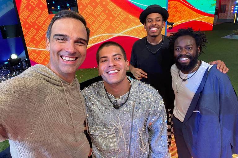 Em foto colorida, quatro homens aparecem sorrindo para selfie em gramado