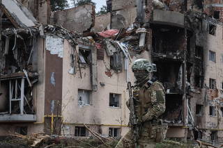 A Ukrainian serviceman is seen near buildings destroyed by Russian shelling in the town of Irpin