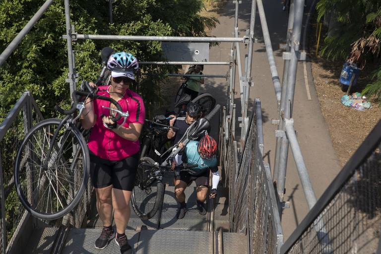 Ciclistas carregam bikes em subida de escada