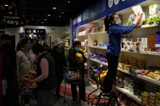 Staff member sorts snacks as customers shop at a supermarket featuring Russian goods in Beijing