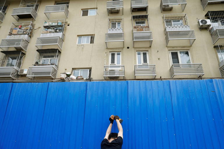Funcionário instala barreira para isolar complexo residencial em Pequim 