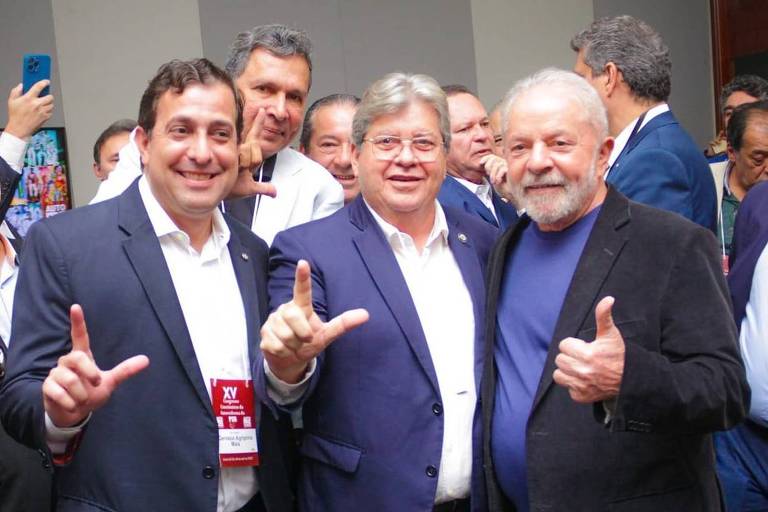 Governador da Paraíba, João Azevêdo (PSB), ao centro, fazendo L alusivo a Lula com a mão ao lado do ex-presidente, que acena com legal com uma mão