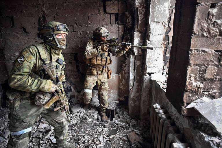 Soldados russos nas ruínas do teatro de drama de Mariupol, destruído durante batalha pela cidade