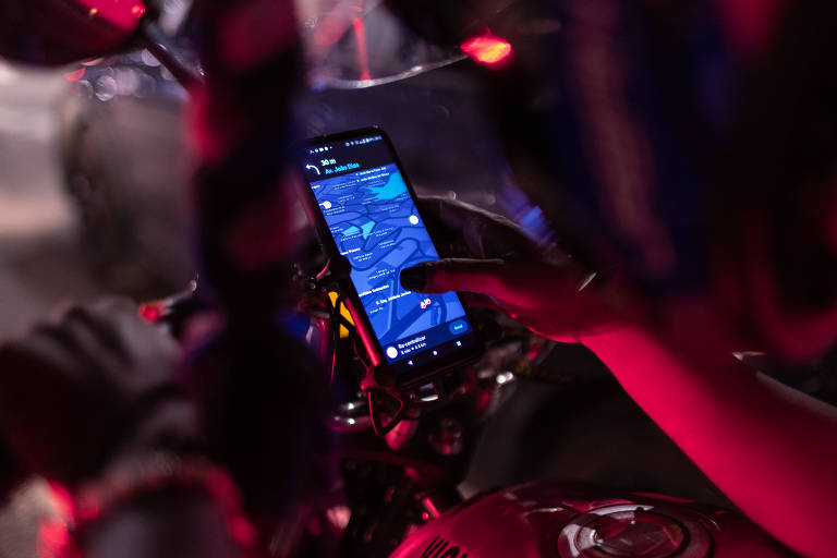 SAO PAULO, SP, 20.02.2022 - Juliana Iemanjara dos Santos, 34 anos, trabalha como entregadora de aplicativos como iFood, LalaMove, ClickEntrega e AppJusto desde 2019. Cria seus dois filhos sozinha, com a ajuda de sua mãe, no bairro da Vila Inglesa, na Zona Sul de São Paulo. Para complementar sua renda trabalha também como em bares, além de vender produtos pela internet e doces pela cidade. Juliana é ativista do coletivo ?Entregadores Anti-Fascistas? e formada em relações humanas e contabilidade. Na foto, Juliana prepara ajusta a rota de entrega durante uma pausa no farol, na Zona Sul de São Paulo. (Foto: Rafael Vilela / Fairwork) *NÃO USAR SEM AUTORIZAÇÃO DO NÚCLEO DE IMAGEM.