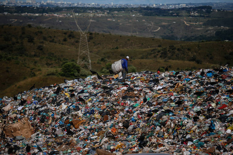 Catador de recicláveis anda sobre lixo no lixão de Águas Lindas de Goias 