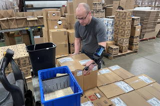 A worker uses an arm-mounted scanner to pack an order at Kem Krest's warehouse in Elkhart
