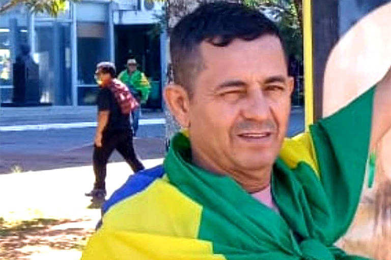 Arnaldo Campos Garcia veste uma camiseta rosa, e tem uma bandeira do Brasil por sobre os ombros