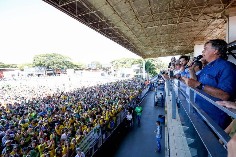 Bolsonaro, em uma sacada do lado direito da foto, discursa e acena para centenas de pessoas 
