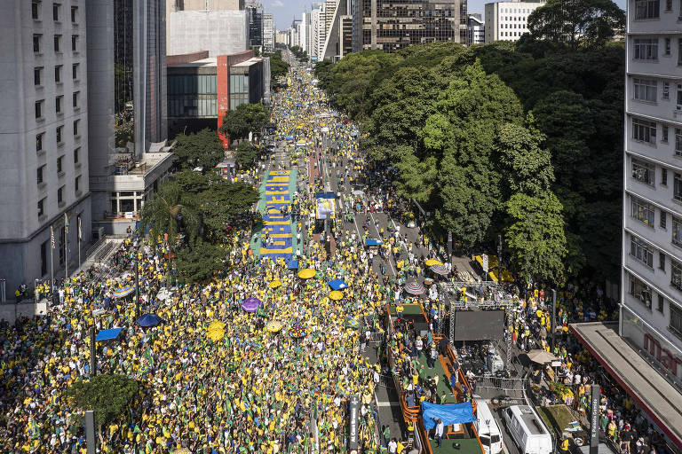 Imagem colorida mostra a avenida Paulista, antes do Masp, com perspectiva para o sentido Paraíso. A via está ocupada por manifestantes pró-Bolsonaro, que se vestem em tons de verde e amarelo. Apesar da concentração, quantidade de pessoas presentes é menor do que o registrado nos atos em setembro de 2021.