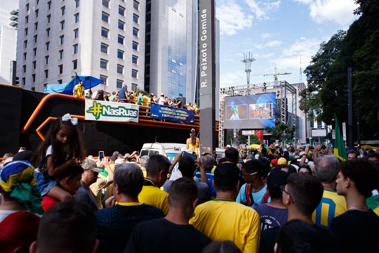 Foto mostra manifestantes espalhados na Avenida Paulista, ao fundo telão exibe a imagem de Jair Bolsonaro