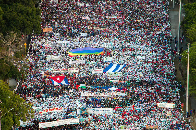 Manifestantes com bandeiras e cartazes no desfile em celebração do Dia do Trabalho, em Havana