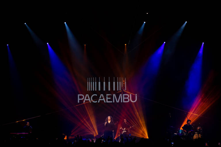 cantora se apresenta em show; atrás dela, projeção de imagem com a logo "Pacaembu"