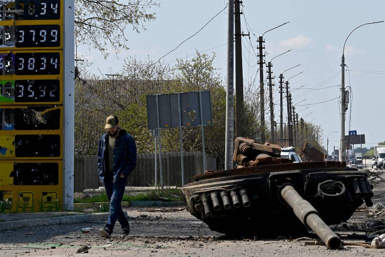 Soldado ucraniano passa perto de torre de tanque russo junto a posto de gasolina em Skibin, nordeste de Kiev

