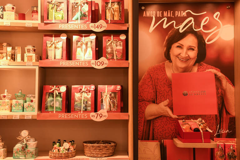 vitrine de loja de cosméticos traz cartaz com mulher vestida de vermelho, sorrindo