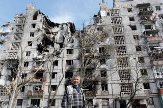 A local resident speaks near a damaged block of flats in Mariupol