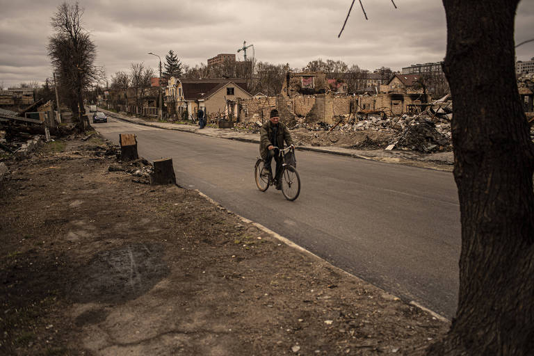 Morador da cidade de Bucha anda de bicicleta na rua Vokzalna, que liga a cidade a Irpin e depois a Kiev